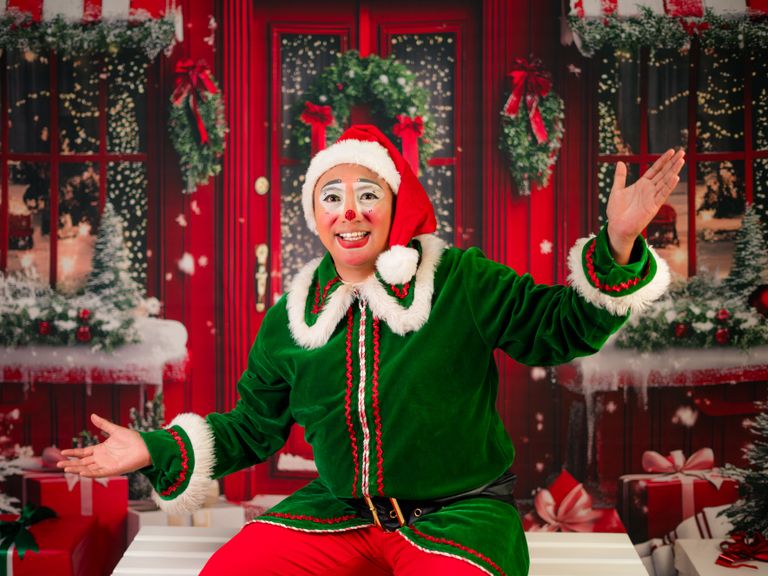 Cheerful clown dressed as an elf in a vibrant Christmas setting.